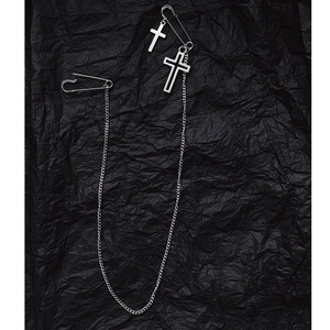 Broche chaîne argentée punk avec épingles de sûreté et doubles croix sur fond noir plissé
