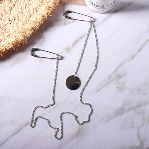 Close-up of punk silver chain brooch with two pins and round metal pendant detail