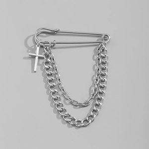 Detail of silver punk safety pin brooch with hanging double chains and cross pendant