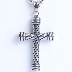 Gros plan sur le pendentif croix en acier inoxydable vintage avec texture spirale