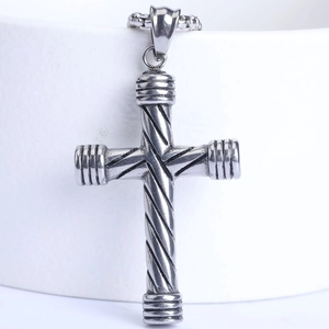 Détail macro du pendentif croix en acier inoxydable argenté avec texture torsadée