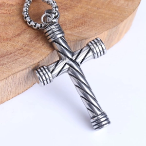 Détail d'un pendentif croix torsadé en acier inoxydable sur un bloc de bois rustique