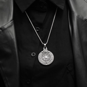 Close-up of a vintage steel talisman pendant necklace on a man wearing a leather jacket