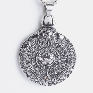Detailed macro of vintage stainless steel pendant featuring relief Sanskrit inscriptions