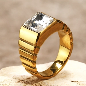 Détail macro d'une bague en titane doré avec pierre carrée transparente et anneau texturé