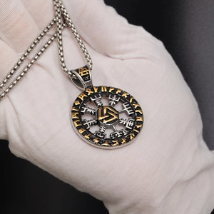 Macro shot of Viking Valknut pendant with golden runes on a polished steel shield