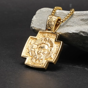 Gouden orthodox kruisbeeld hanger met Jezus reliëf op een grijze natuursteen ondergrond