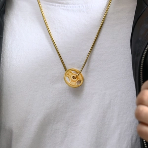 Close-up of gold fitness dumbbell pendant necklace with motivational engraving on male model