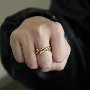 Detailed view of a gold woven thorn-style ring worn on the finger with a modern design