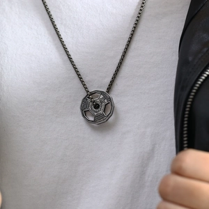 Macro shot of barbell plate pendant with fitness quote and box chain on neck
