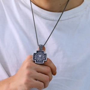 Detail van vintage religieuze kruishanger met reliëf op een vierkante parelketting
