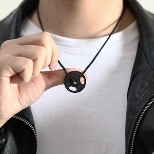 Close-up of a matte black dumbbell weight plate necklace with Fitness engraving for men
