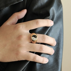 Detailed view of punk style gold Yin Yang ring with black and white crystals on finger