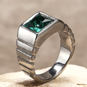 Détail d'une bague pour homme en argent avec une grande pierre verte et texture en escalier