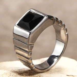 Vue macro d'une bague en acier titane argenté avec pierre noire rectangulaire et bords striés