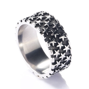 Bague large punk en acier inoxydable avec étoiles gaufrées vintage sur fond noir texturé