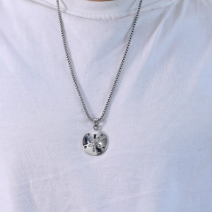 Minimalist stainless steel circular floral hollow pendant necklace on a white shirt