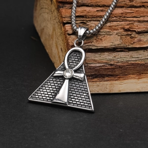 Detail of silver pyramid pendant with Ankh symbol and sparkling crystal on wood