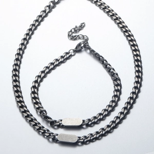 Detailed macro view of vintage silver Cuban link necklace and bracelet with engraving plate