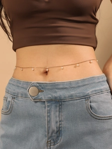 Détail d'une élégante chaîne de taille dorée à glands de perles sur un mannequin
