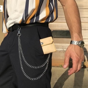 Détail d'un portefeuille en cuir marron clair avec double chaîne argentée sur jean