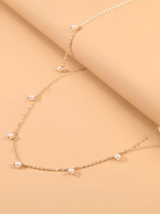 Détail d'une élégante chaîne de taille dorée avec de délicates perles nacrées et pompon