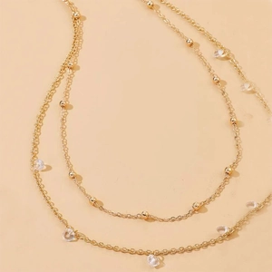 Detail of a golden double-layer waist chain with beads and sparkling zircon pendants
