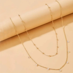 Double-layered gold waist chain featuring small beads and zircon tassel pendants