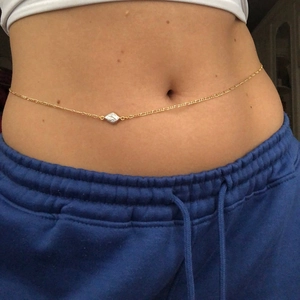 Detail einer goldenen Taillenkette mit rautenförmigem Anhänger an einer weiblichen Taille
