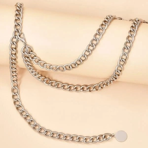 Détail d'une chaîne de taille argentée multicouche avec pendentif rond et fermoir