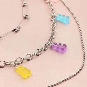 Layered silver metal chain necklace with colorful resin gummy bears and safety pin accents