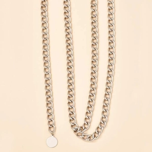 Chaîne de taille à maillons cubains argentés avec pendentif rond sur fond beige clair neutre