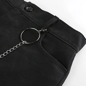 Détail macro de la taille en denim noir avec texture sergée et anneaux de chaîne punk