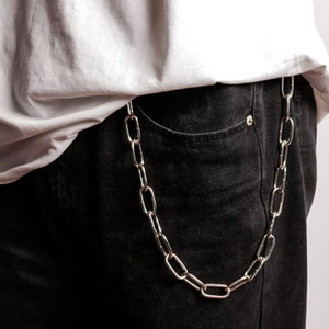 Détail d'une chaîne de pantalon à maillons longs en métal argenté sur un jean noir