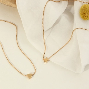 Close-up of golden beaded body chains featuring polished heart and star shaped pendants