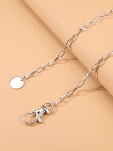 Macro detail of silver metal chain belt with lobster clasp and round pendant charm