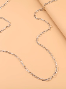 Detailed view of silver-tone paperclip chain accessory on a minimalist background