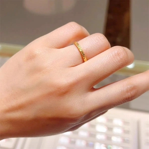 Close-up of golden ring with hammered texture worn on finger in elegant jewelry store