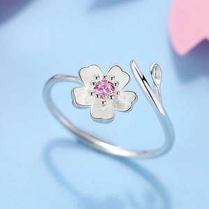 Macro shot of silver sakura ring with pink zircon center and white enamel petals