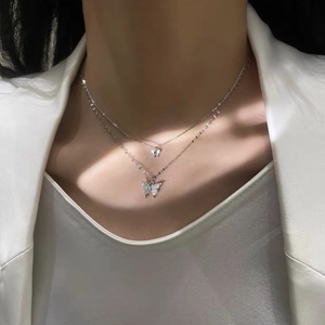 Détail du collier papillon argenté à double couche avec pavé de zircons sur le modèle