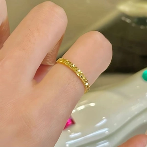 Macro shot of a thin gold sparkling ring featuring a starry hammer texture on the finger