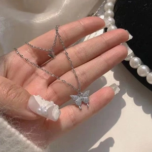 Gros plan sur un collier double couche avec pendentif papillon et strass brillants pour femme