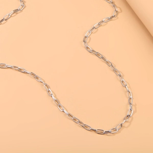 Polished silver paperclip chain belt with round pendant on minimalist warm background