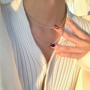 Detail view of a layered silver necklace with starry sand and paperclip chain design