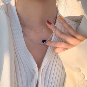 Detail of layered silver snake chain and sparkling zircon tennis necklace on neck
