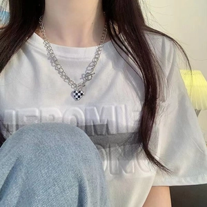 Gros plan du pendentif cœur à damier sur une chaîne argentée avec fermoir à bascule