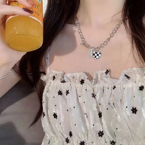 Détail du collier à chaîne argentée avec pendentif coeur damier et plaque en métal