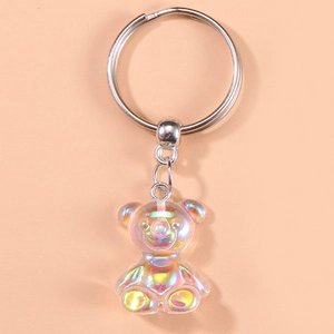 Iridescent bear keychain with bow detail and silver metal ring on orange background