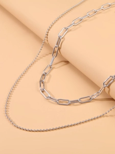 Close-up of double layer silver ball and paperclip chain necklace with metallic finish