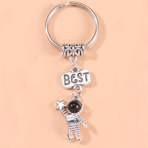 Silver astronaut keychain with star pendant and BEST engraving on a pink background